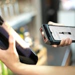 Close-up of a person scanning a wine bottle with a portable scanner in a store.